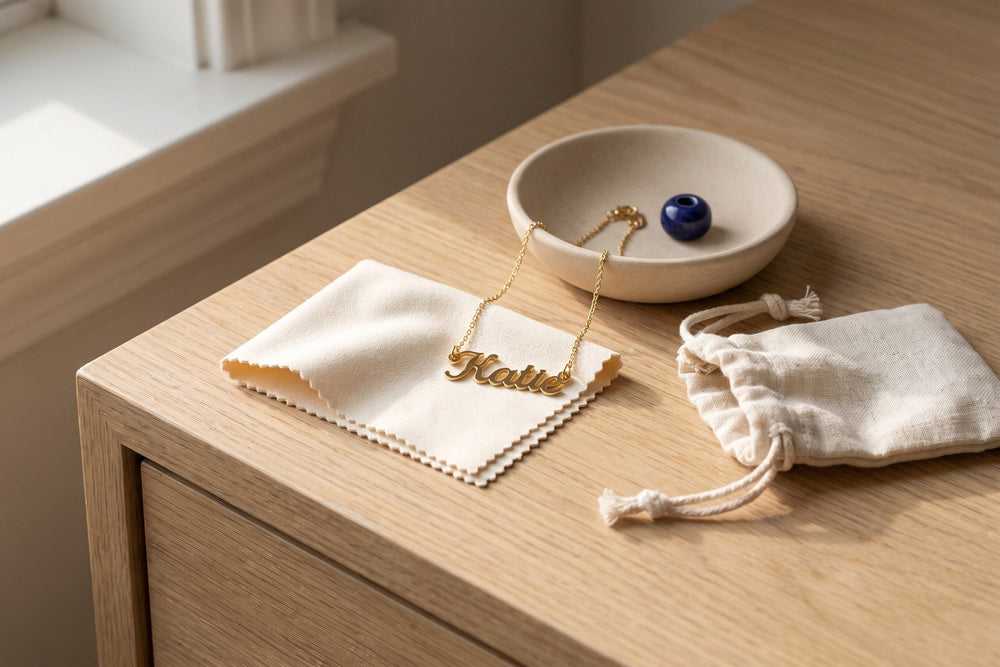 Gold name necklace on a soft polishing cloth beside a linen pouch