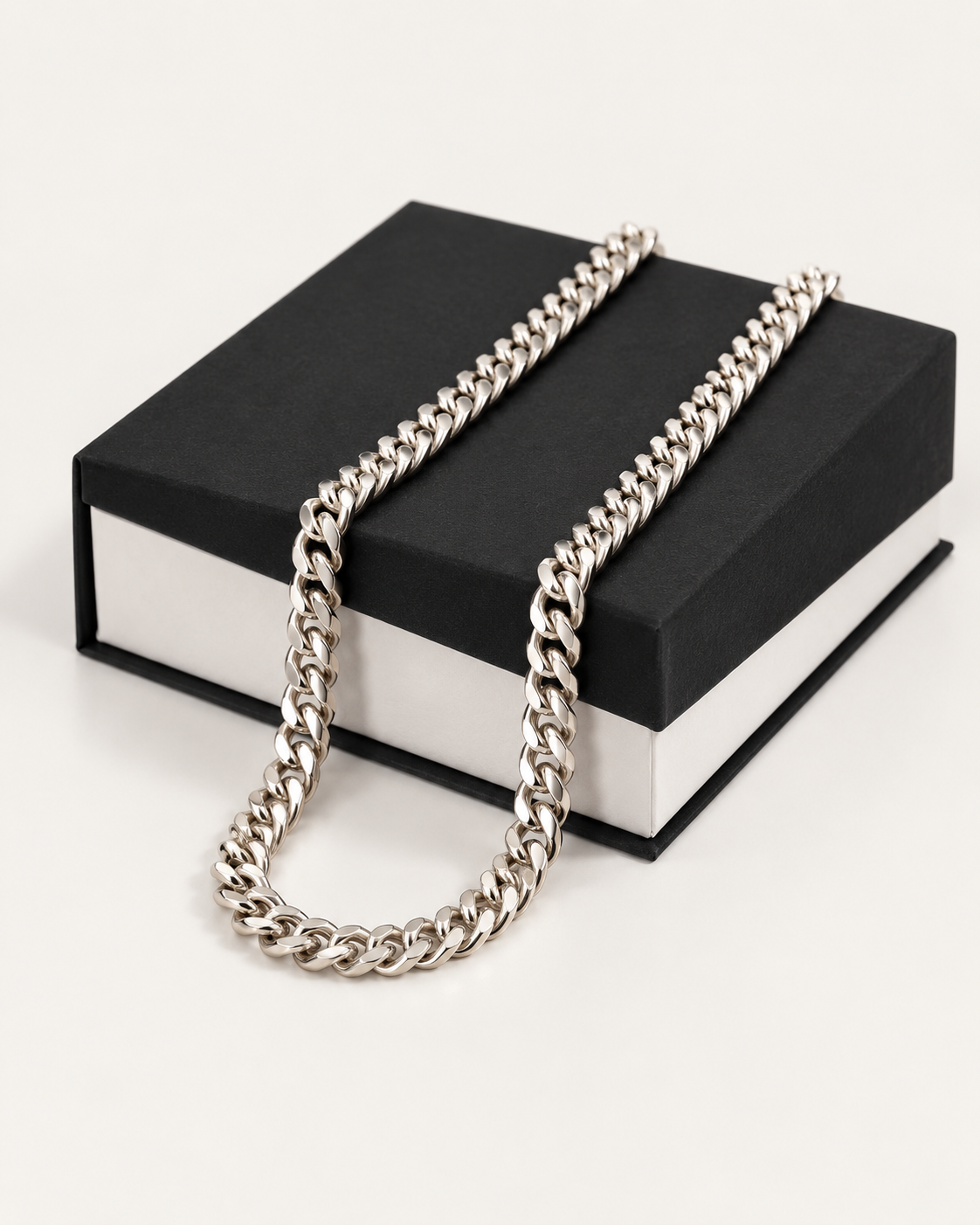 Silver-tone 5 mm Cuban link chain draped across a black gift box.