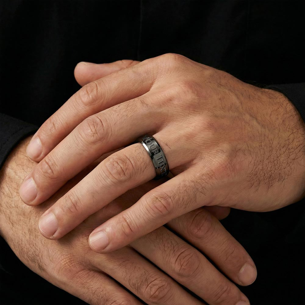 Close-up of a black men's engraved ring on a hand.