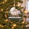 Clear acrylic first Christmas ornament with a teddy in a pink pram and example name Charlotte, hanging on a lit tree.