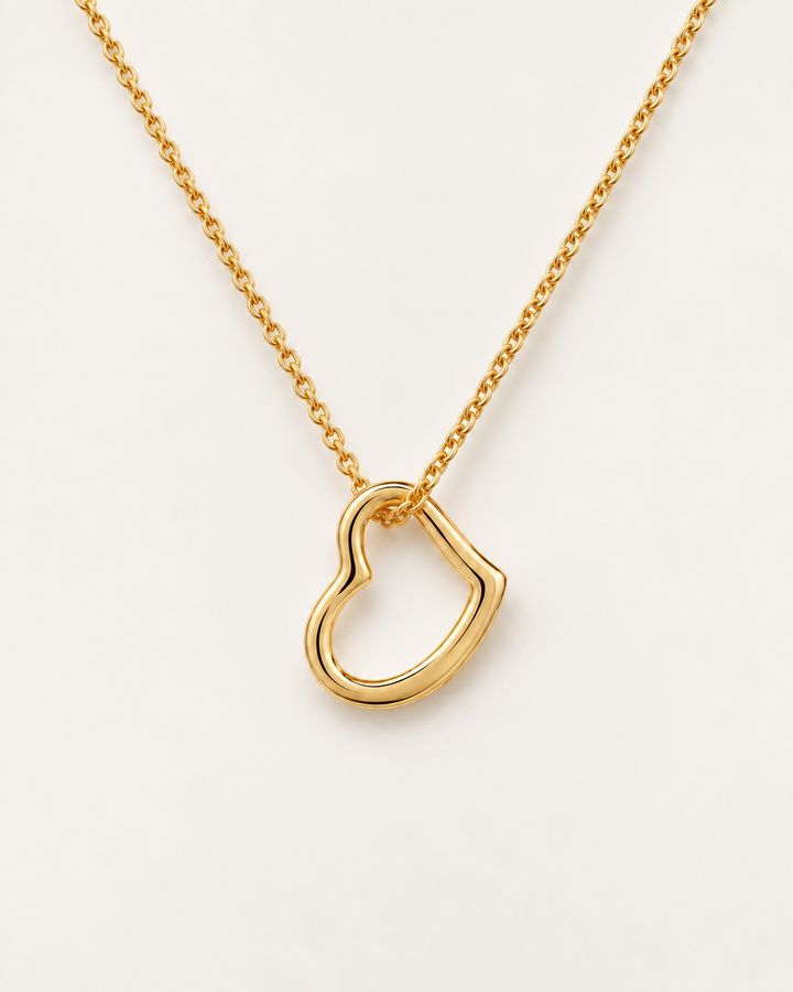 Delicate open-heart necklace in a gold finish on an ivory background.