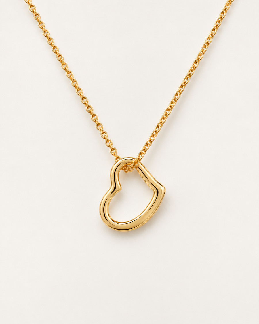 Delicate open-heart necklace in a gold finish on an ivory background.