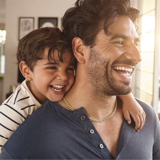 Man smiling with a child on his back.