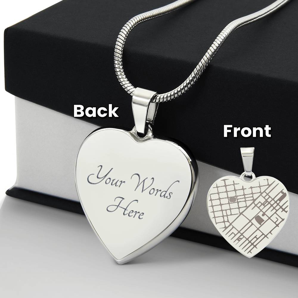 Front and back views of a silver-tone heart map pendant beside a black gift box.