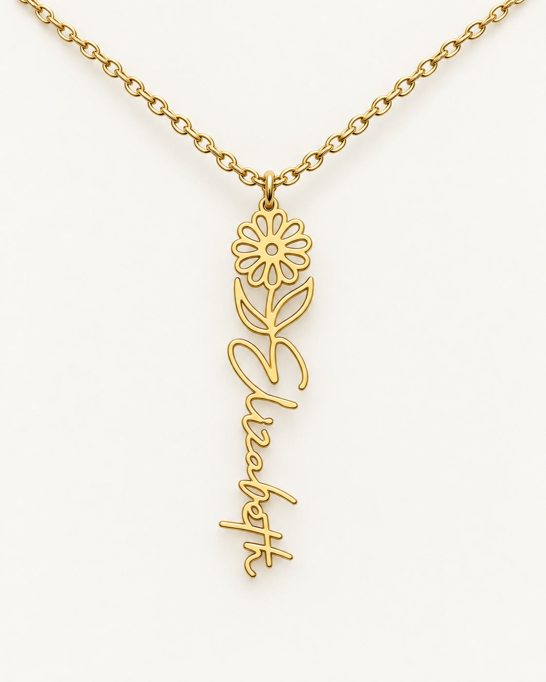Gold-tone birth flower necklace with a daisy motif and vertical script name pendant on ivory.