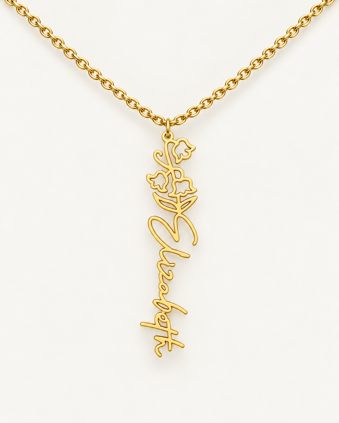 Gold-tone birth flower necklace with a iris motif and vertical script name pendant on ivory.