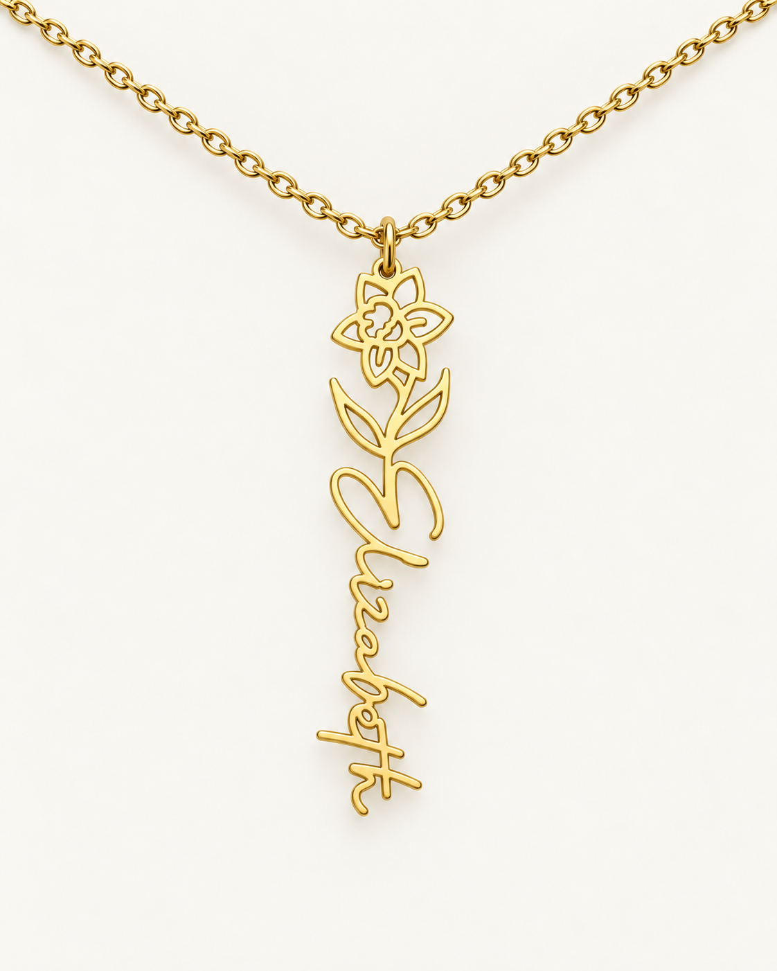 Gold-tone birth flower necklace with a lily of the valley motif and vertical script name pendant on ivory.