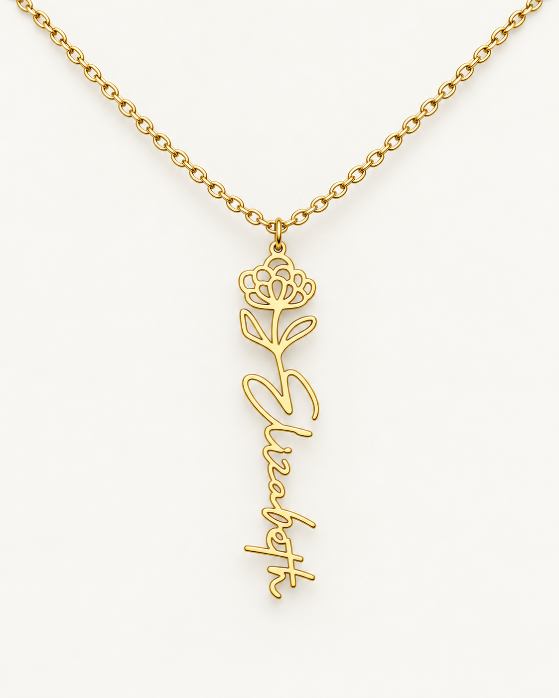 Gold-tone birth flower necklace with a water lily motif and vertical script name pendant on ivory.