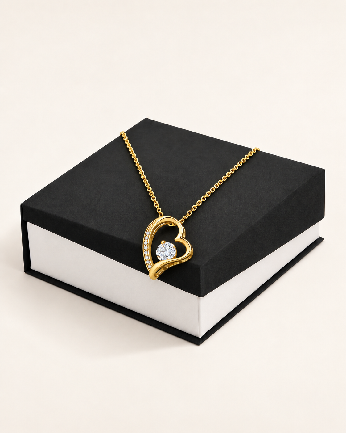Gold-tone classic heart CZ necklace draped across a black gift box.