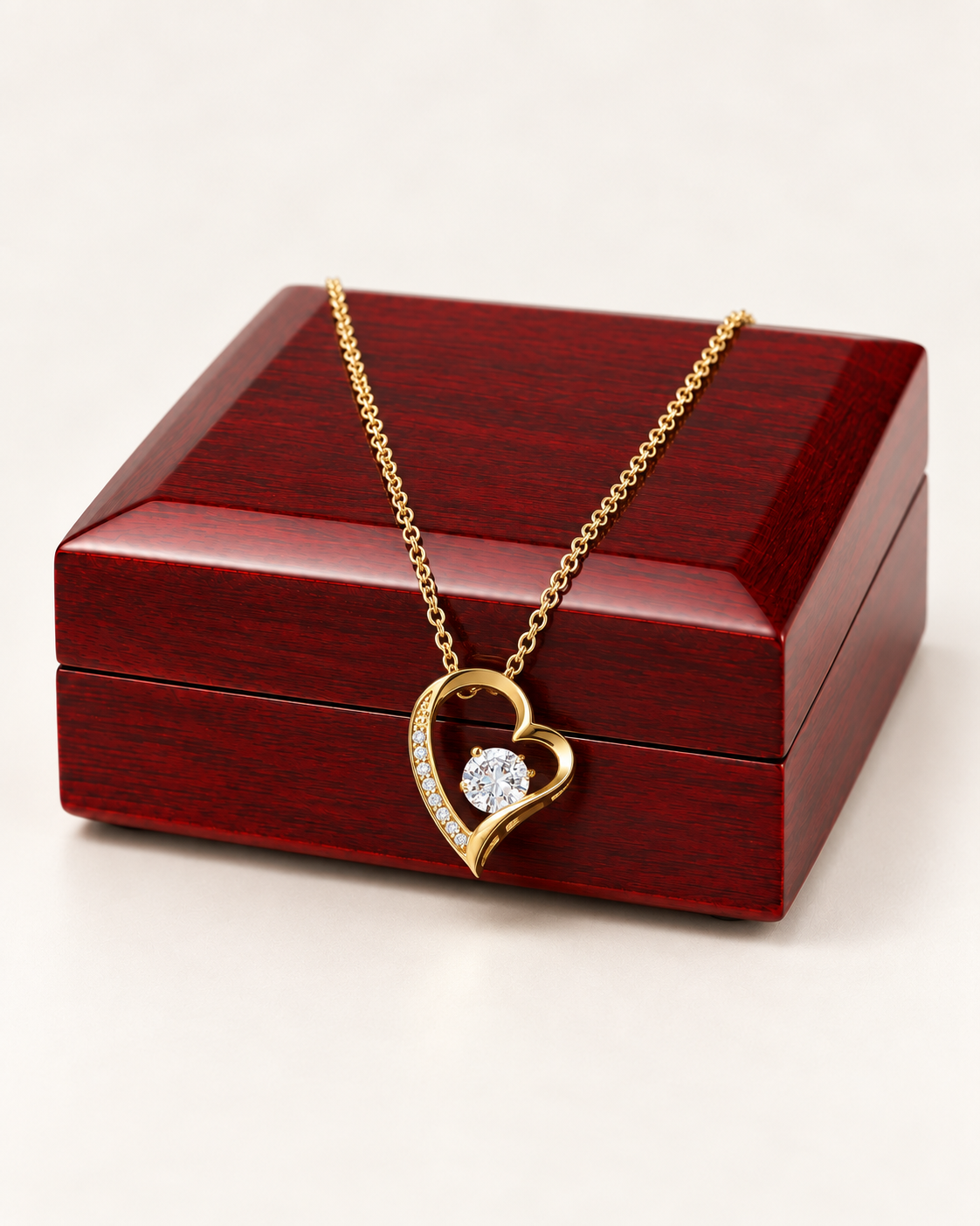 Gold-tone classic heart CZ necklace draped across a wooden gift box.