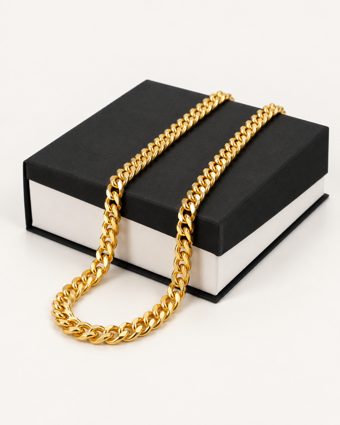 Gold-tone Cuban link chain draped across a black gift box.