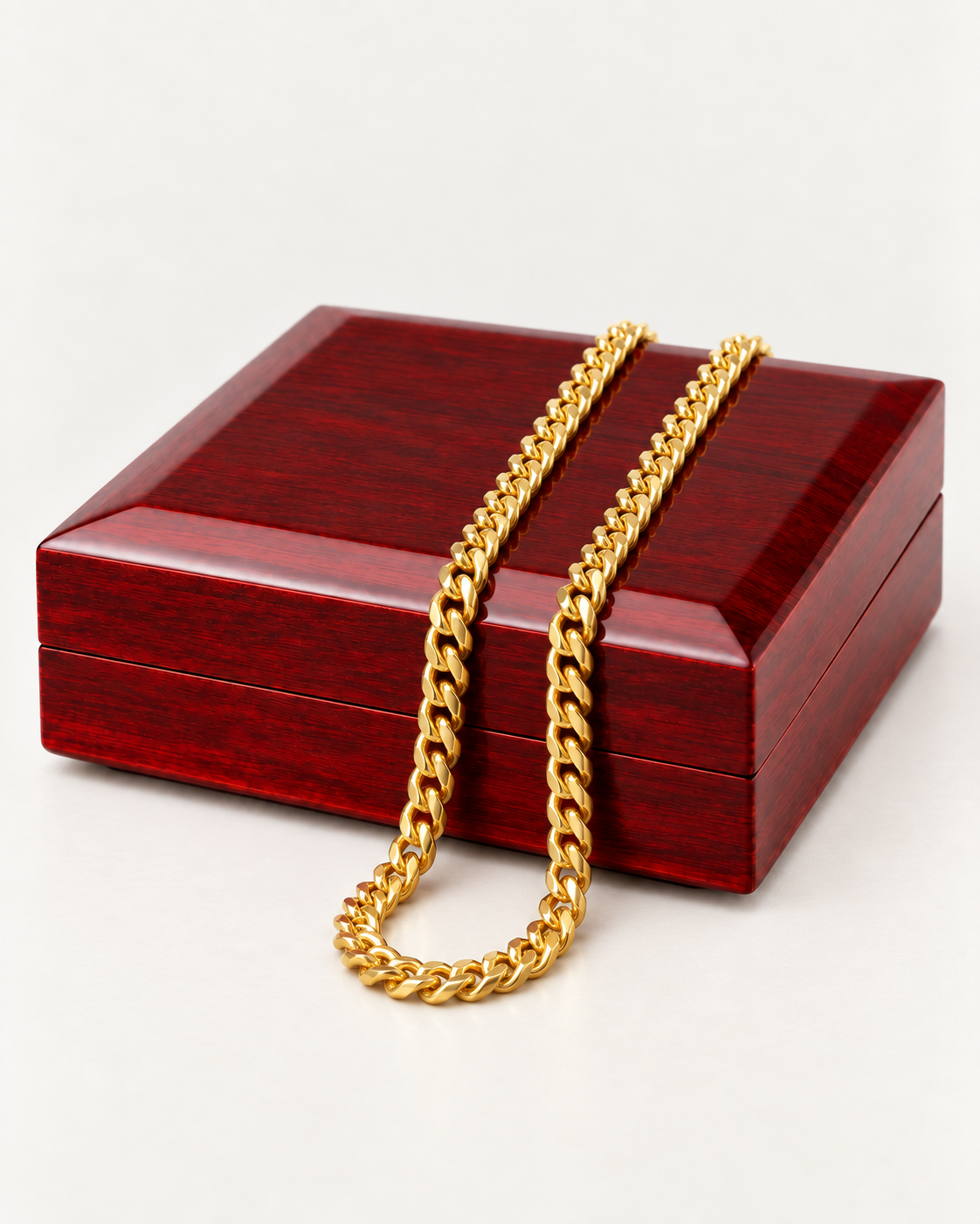Gold-tone Cuban link chain draped across a wooden gift box.