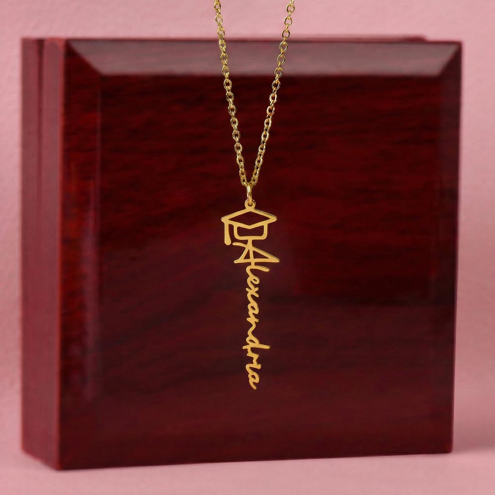 Gold-tone graduation name necklace displayed on a wooden gift box.