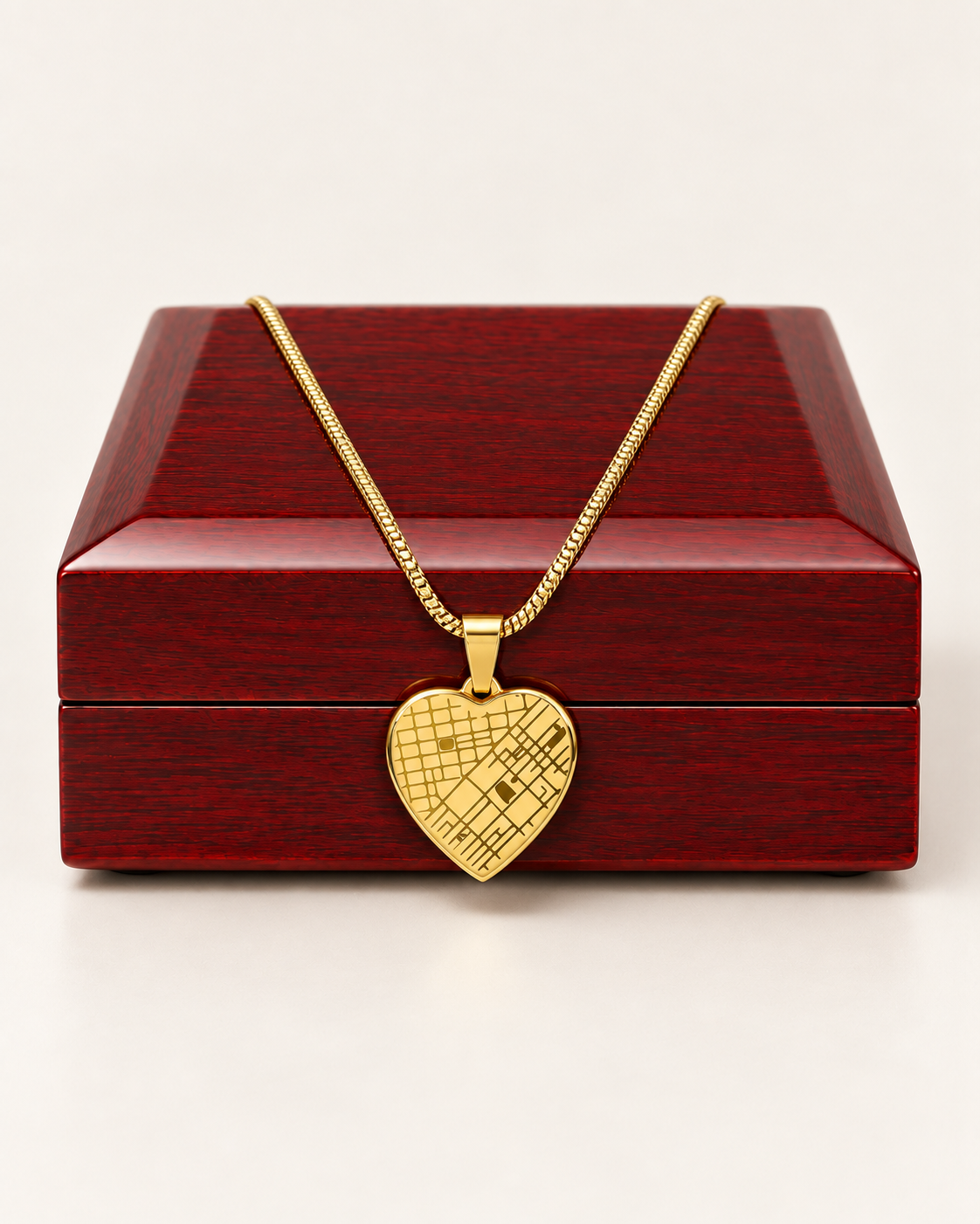Gold-tone heart map necklace draped across a wooden gift box.