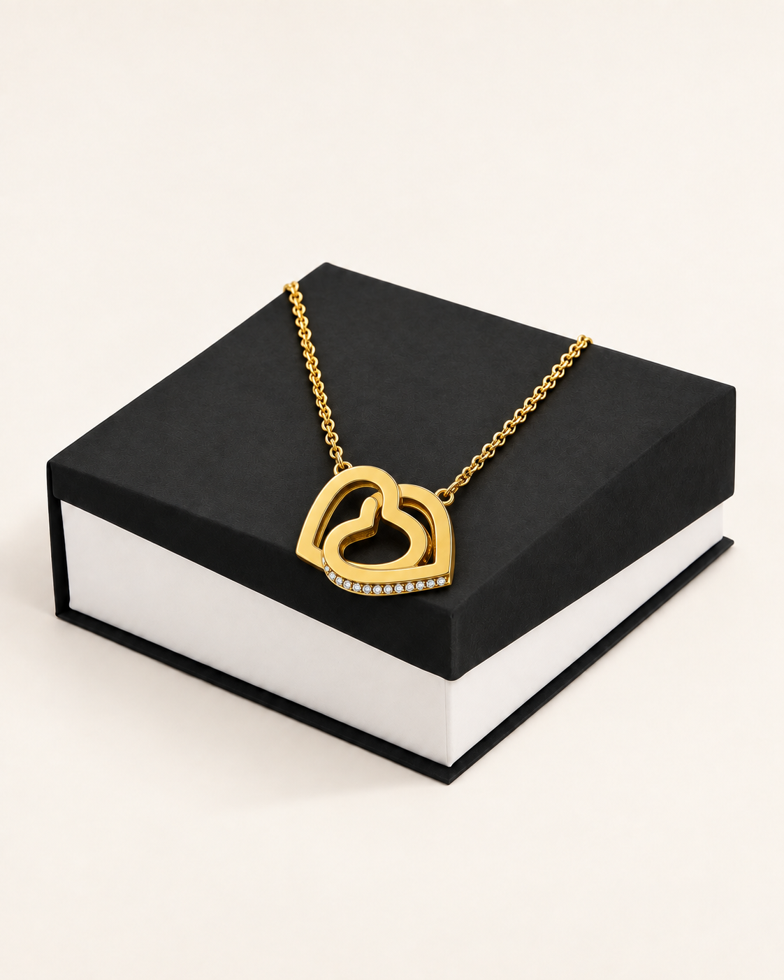 Gold-tone interlocking hearts necklace displayed on a black gift box.