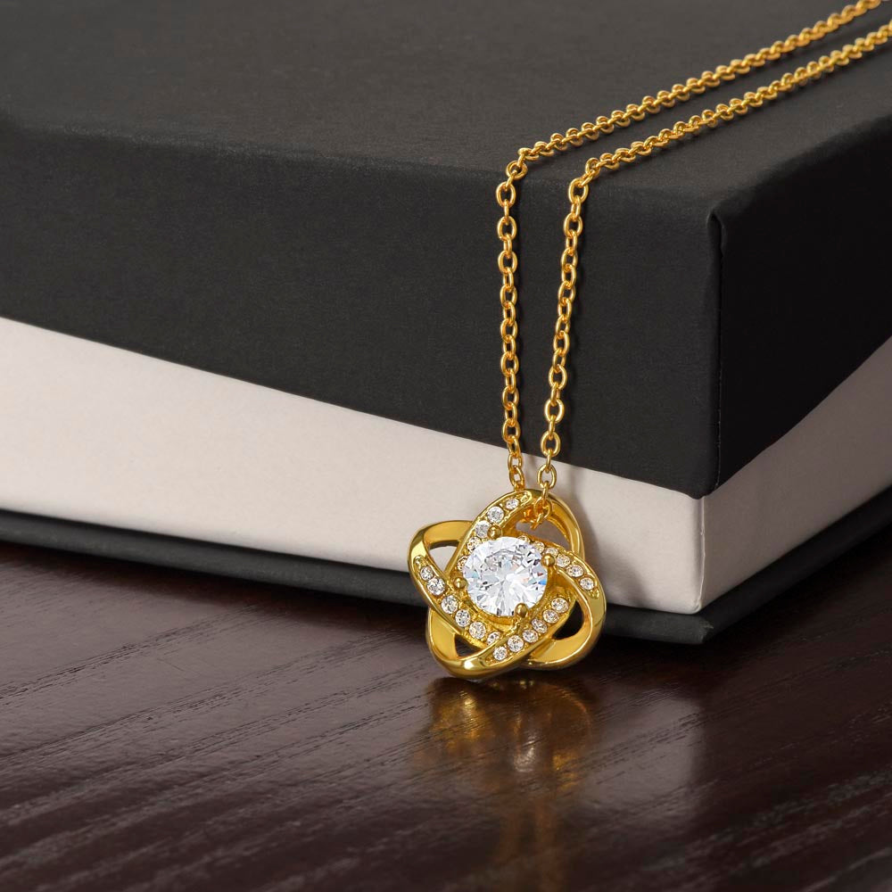 Gold-tone Love Knot CZ necklace displayed against a black gift box.