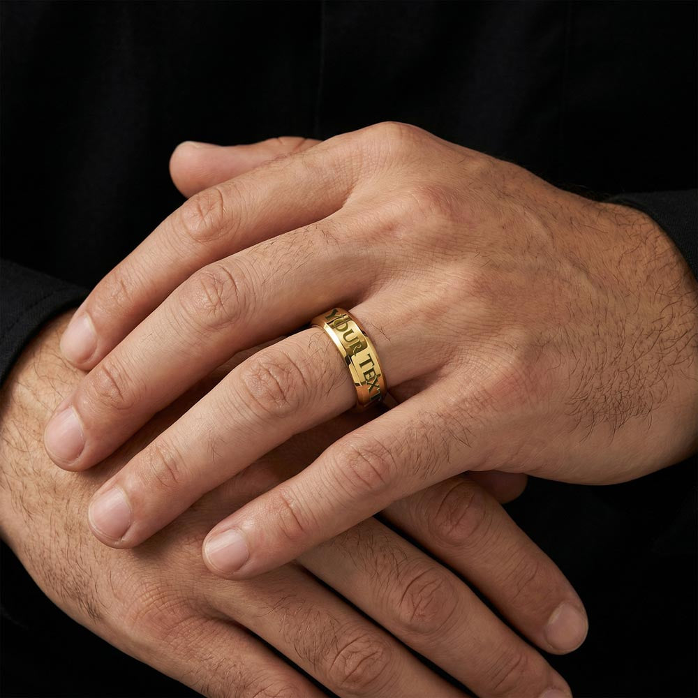 Close-up of a gold-tone men's engraved ring on a hand.