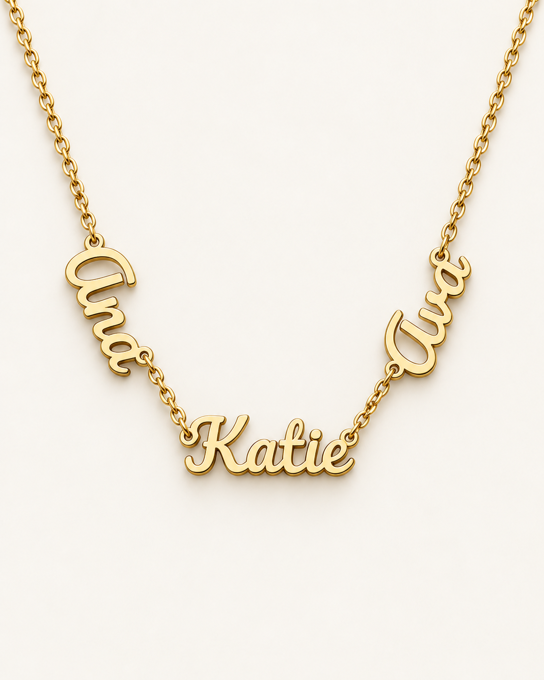 Gold-tone necklace with three connected script name pendants on an ivory background.
