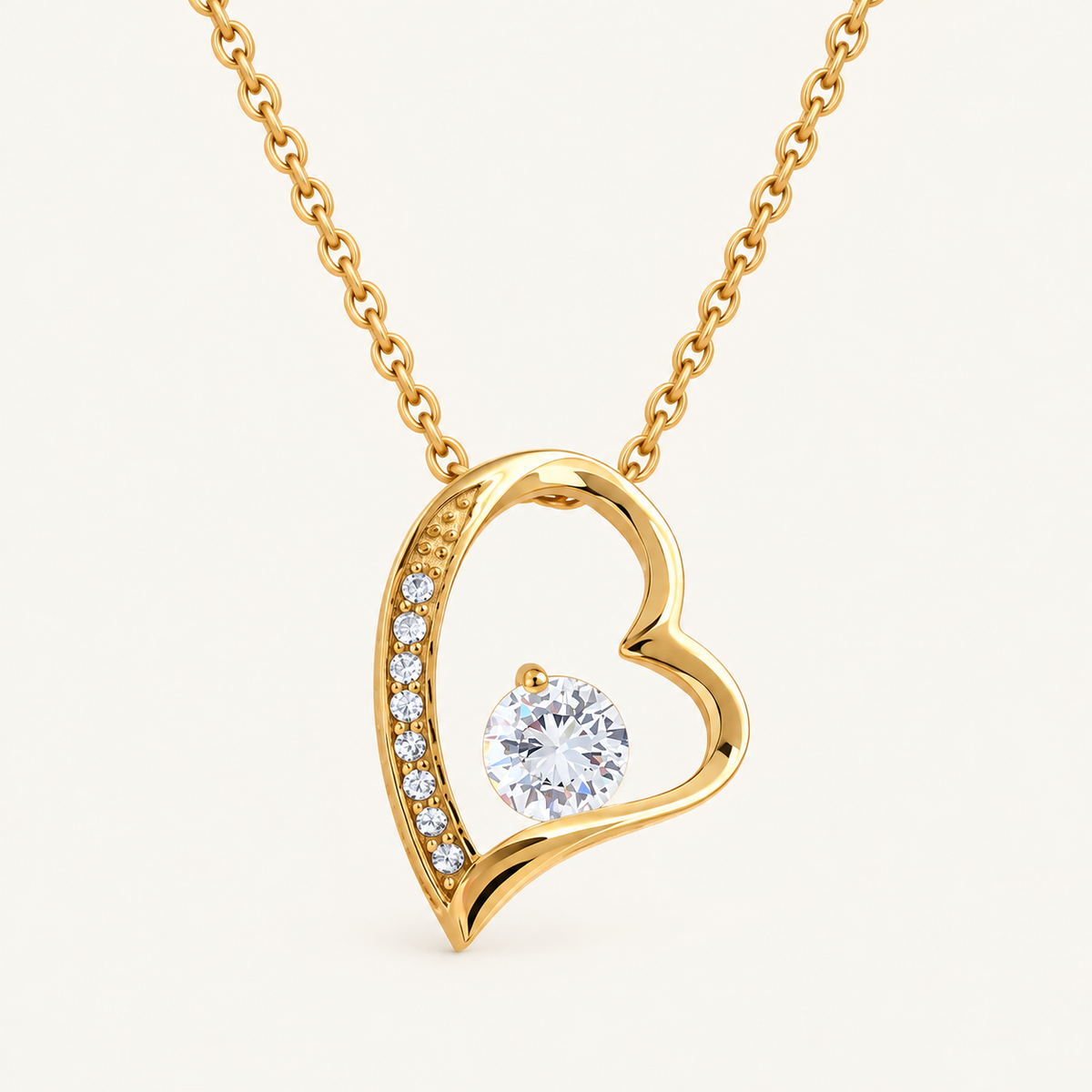 Close-up of a gold-tone open-heart pendant with a round CZ stone and crystal accents.
