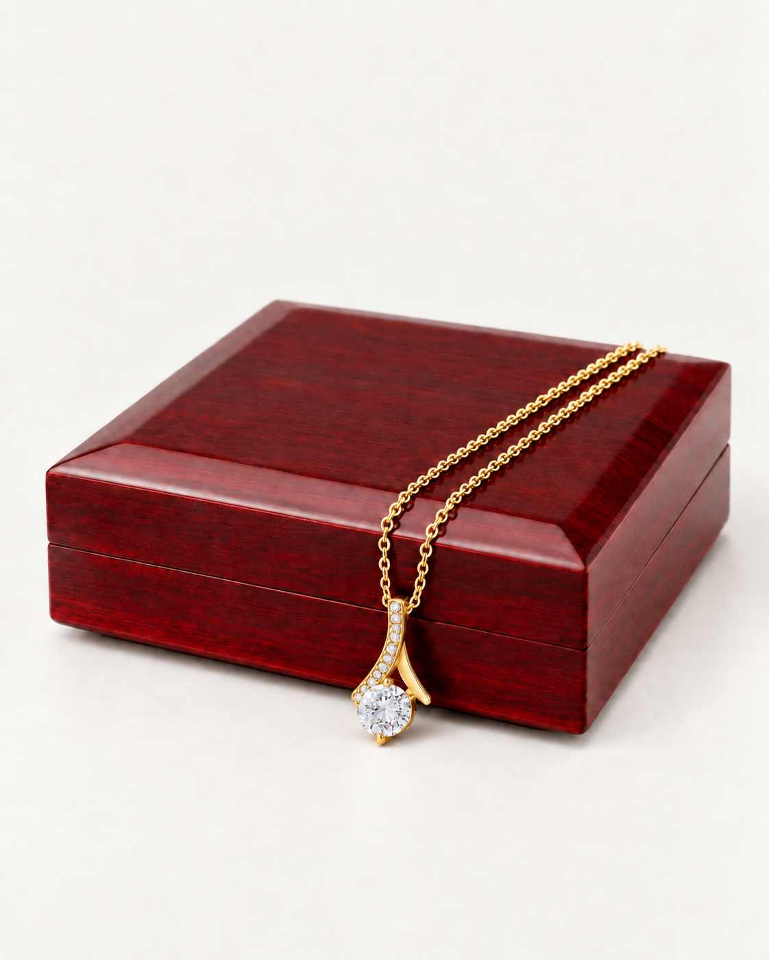 Gold-tone ribbon CZ necklace draped across a wooden gift box.