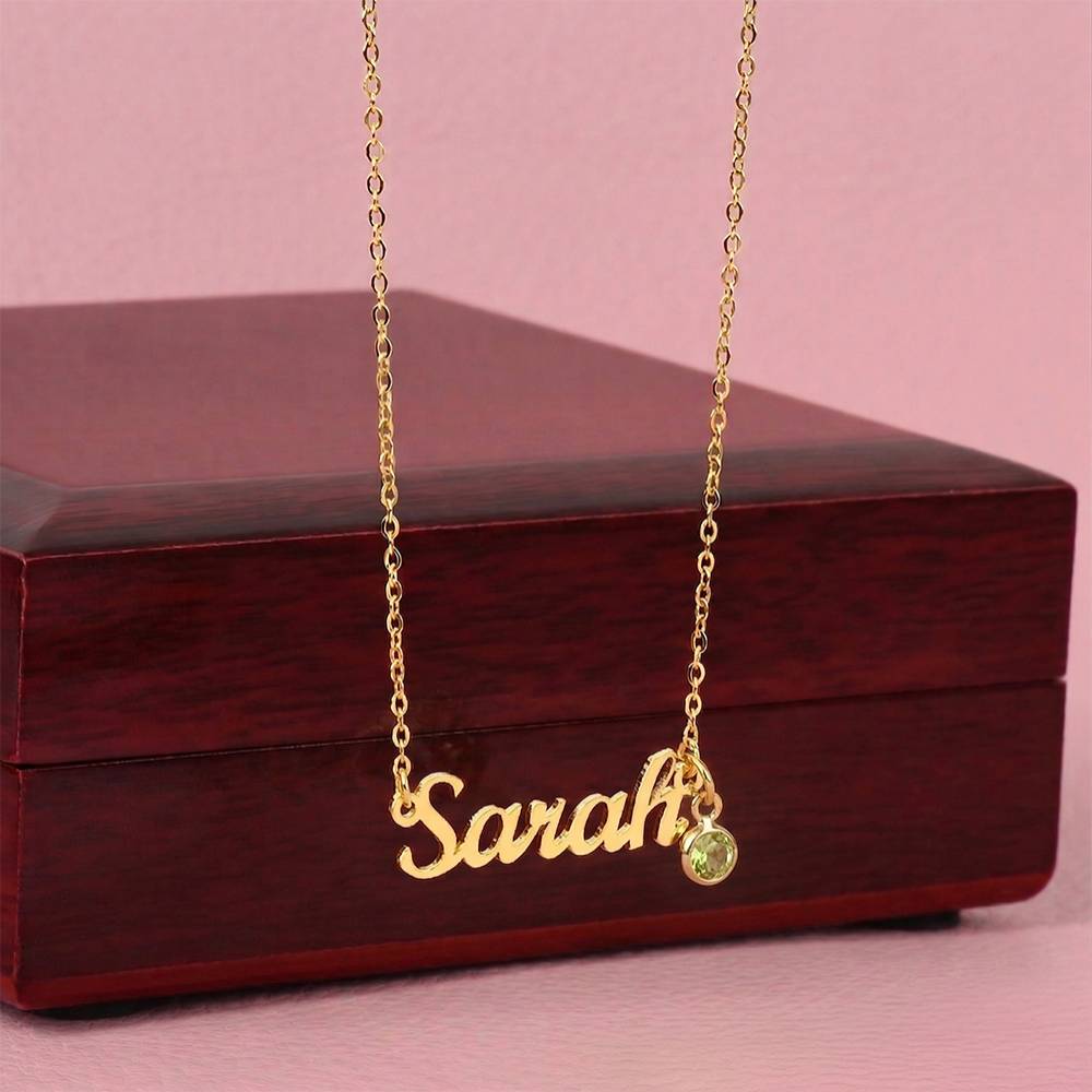 Gold-tone Sarah name necklace with a yellow birthstone displayed against a wooden gift box.