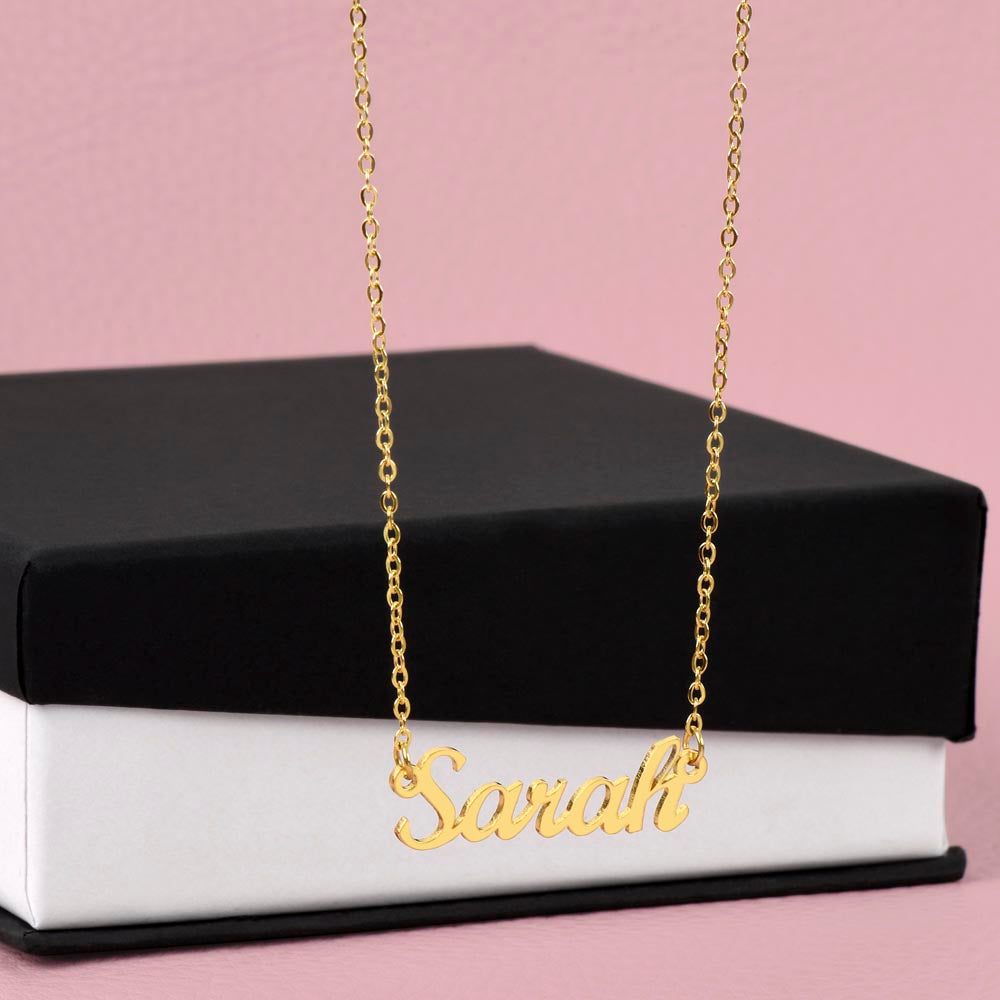 Gold-tone Sarah script name necklace displayed against a black gift box.