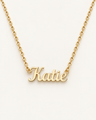 Gold-tone script name necklace with the example name Katie on ivory.