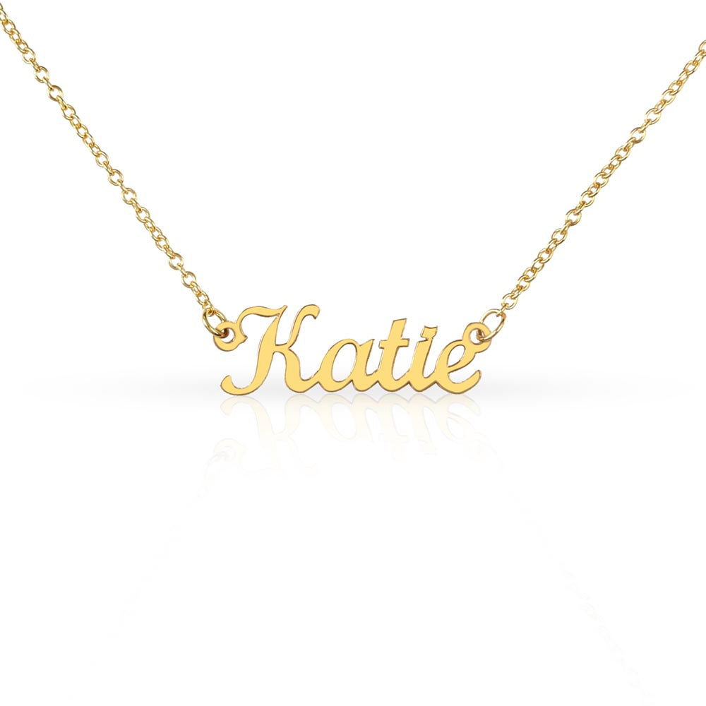 Close-up of a gold-tone script name necklace with the example name Katie.