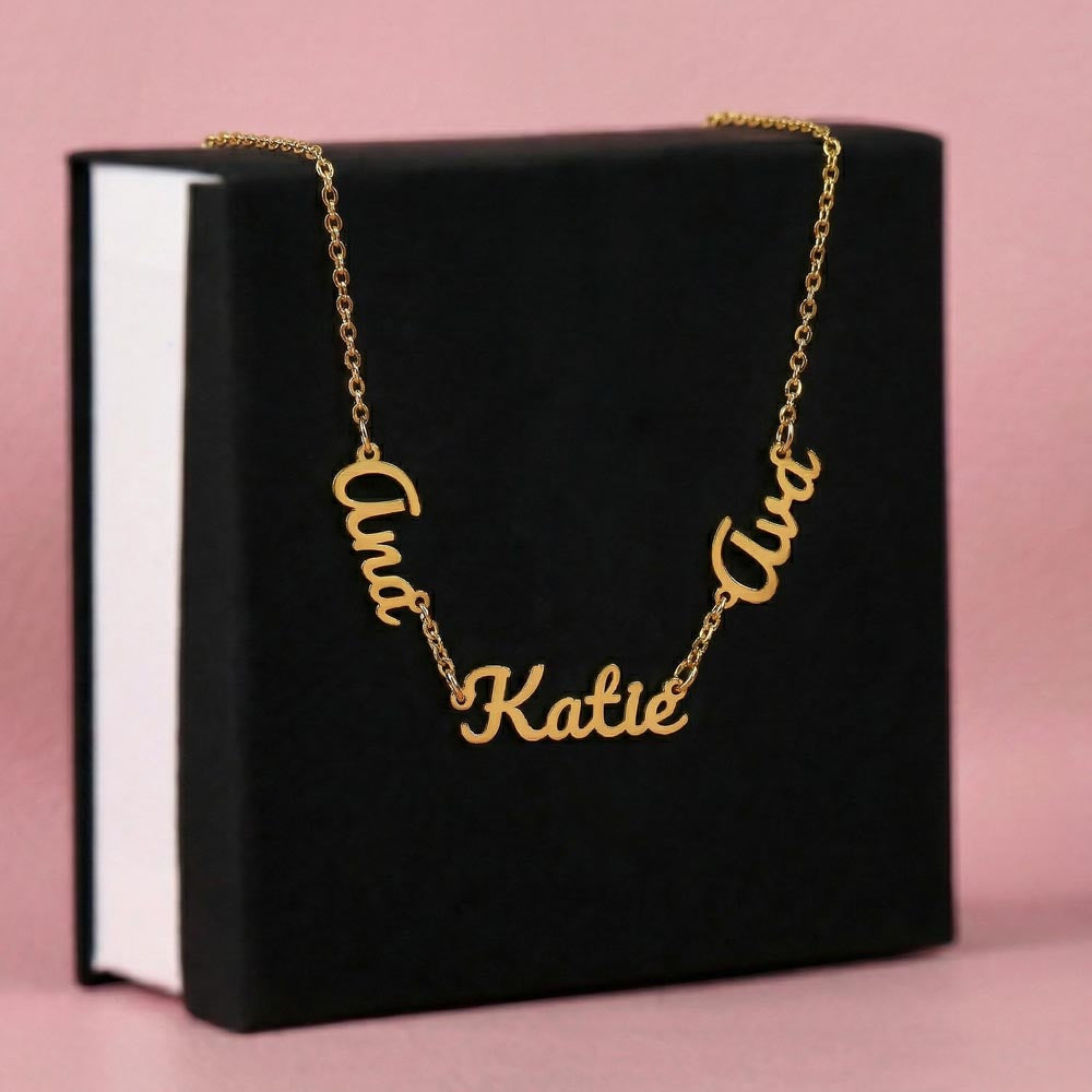 Gold-tone three-name necklace displayed on a black gift box.
