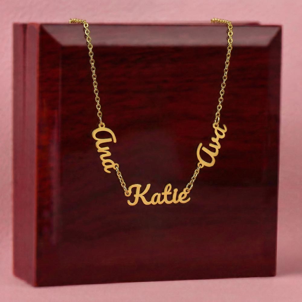 Gold-tone three-name necklace displayed on a wooden gift box.