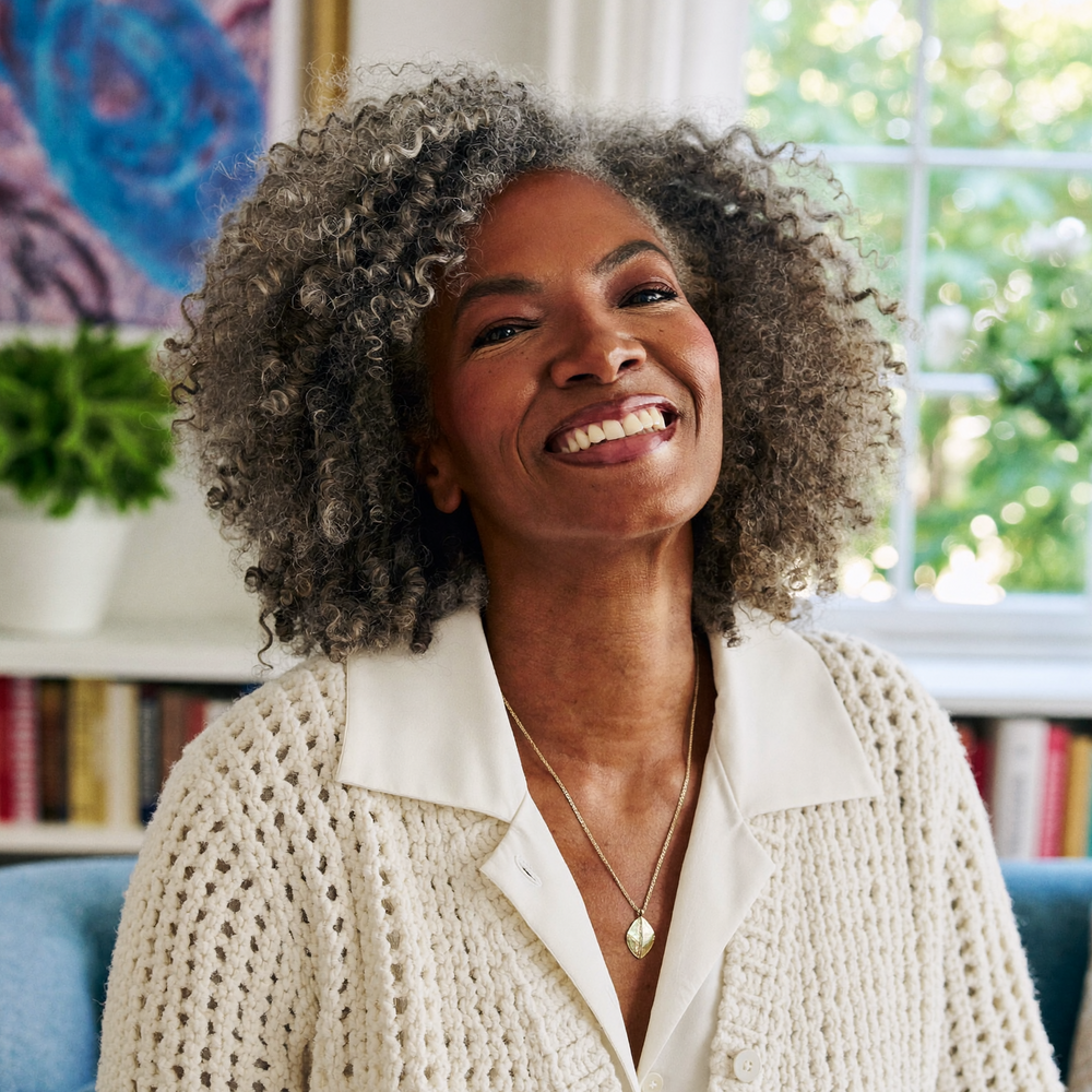 Woman smiling outdoors in an ivory knit cardigan.