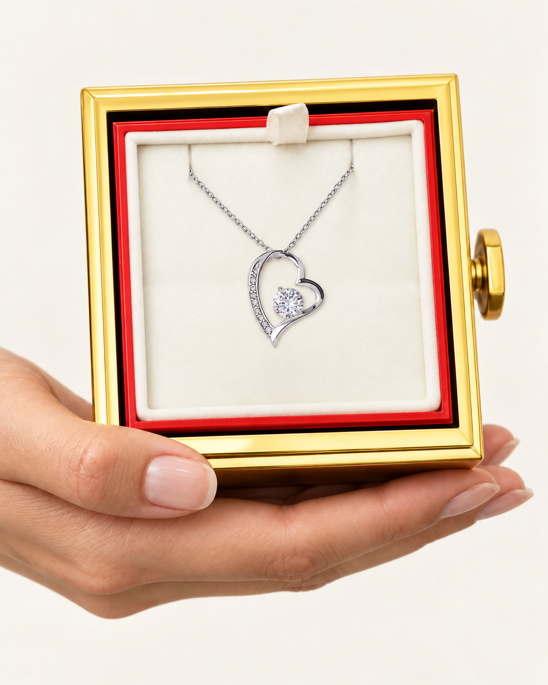 Hand holding an open rotating rose box with a silver-tone classic heart CZ necklace inside.