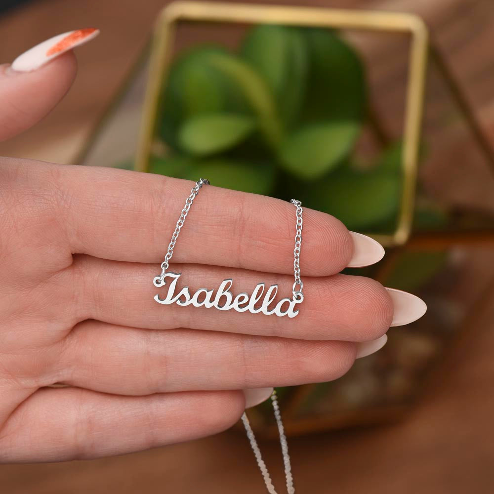 Hand holding a silver-tone Isabella script name necklace to show its scale.