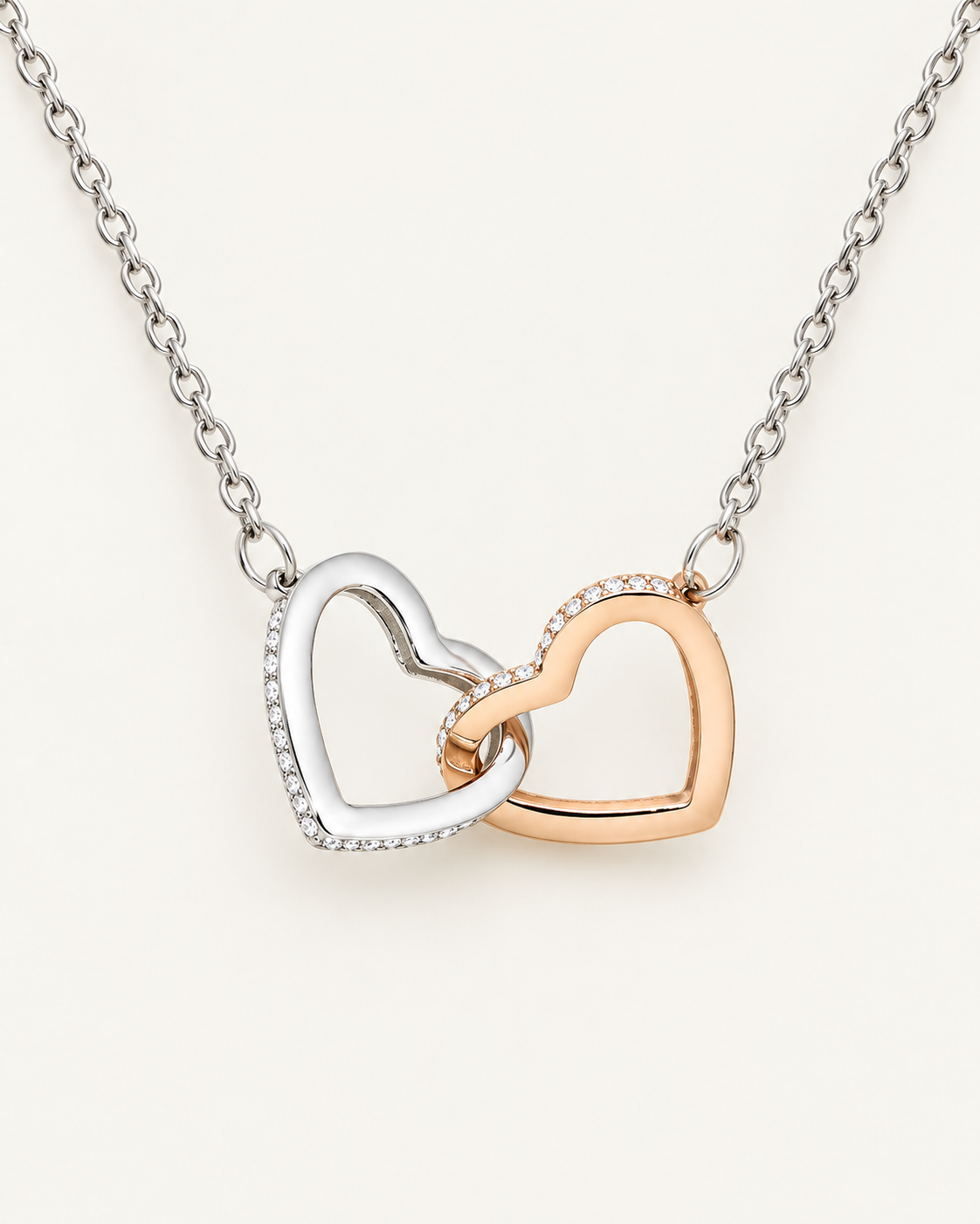 Close-up of interlocking silver-tone and rose-gold-tone heart pendants with crystal accents.