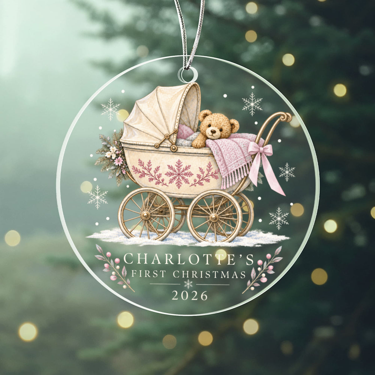 Pink teddy pram first Christmas ornament with example name Charlotte against a soft green background.