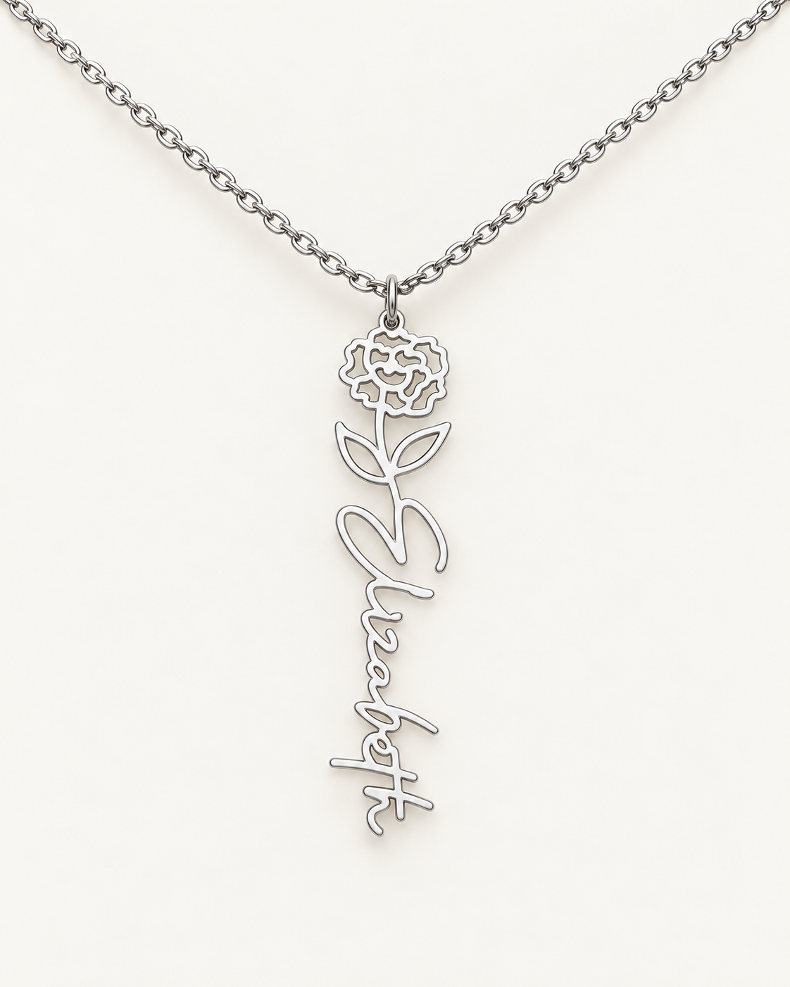 Silver-tone birth flower necklace with a carnation motif and vertical script name pendant on ivory.