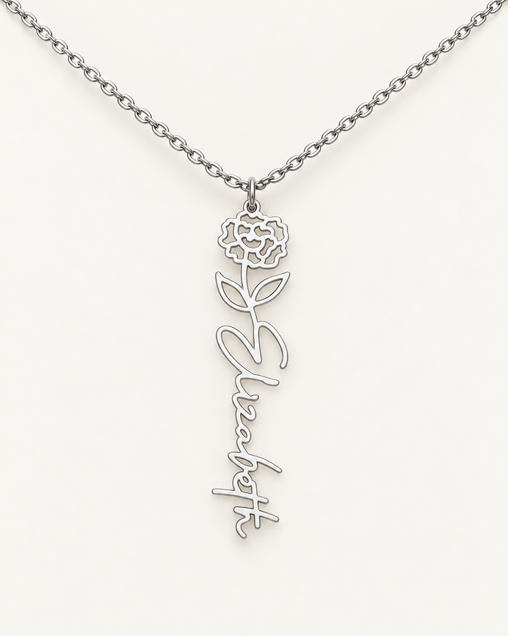 Silver-tone birth flower necklace with a carnation motif and vertical script name pendant on ivory.