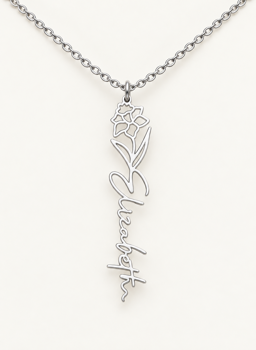 Silver-tone birth flower necklace with a daffodil motif and vertical script name pendant on ivory.