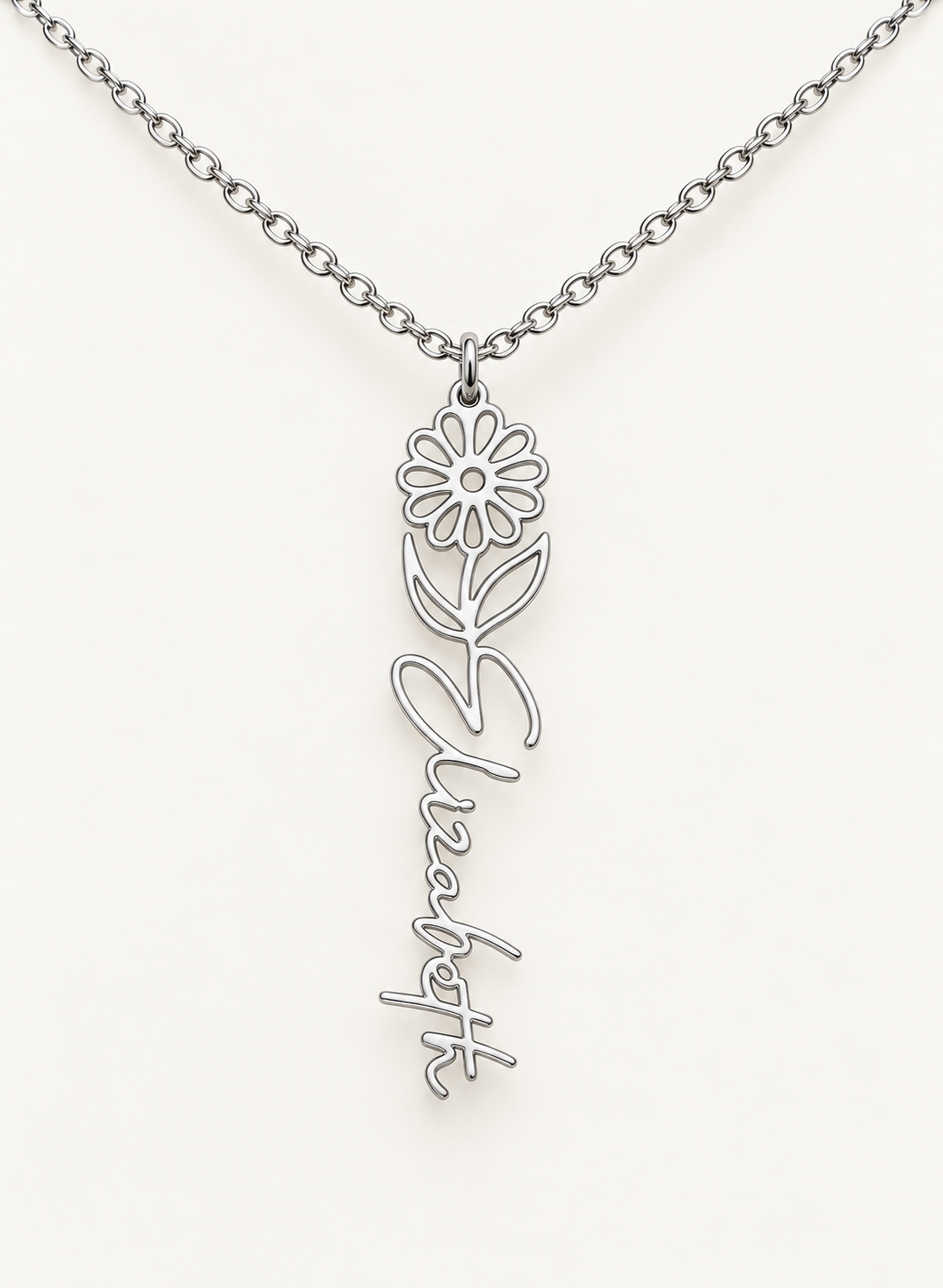Silver-tone birth flower necklace with a daisy motif and vertical script name pendant on ivory.