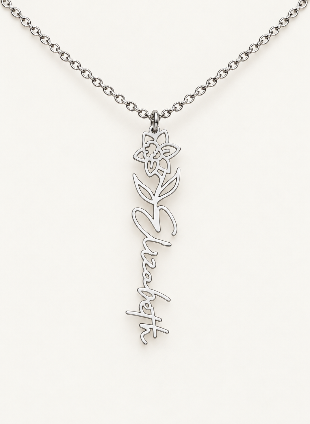 Silver-tone birth flower necklace with a narcissus motif and vertical script name pendant on ivory.