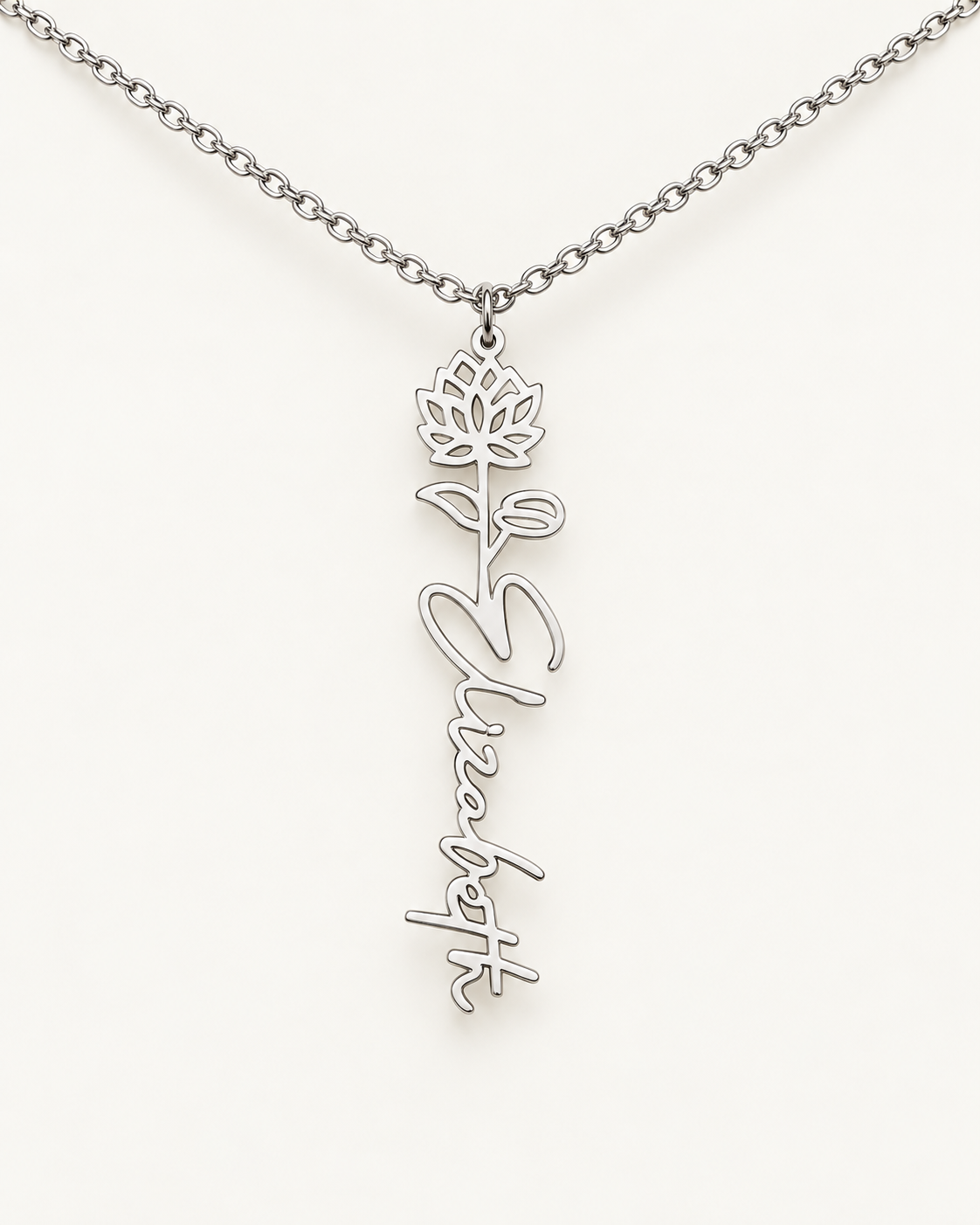 Silver-tone birth flower necklace with a water lily motif and vertical script name pendant on ivory.