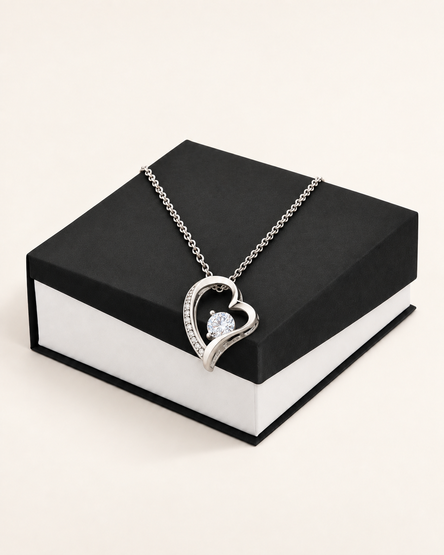 Silver-tone classic heart CZ necklace draped across a black gift box.