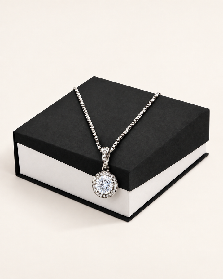 Silver-tone crystal halo pendant necklace displayed on a black gift box.
