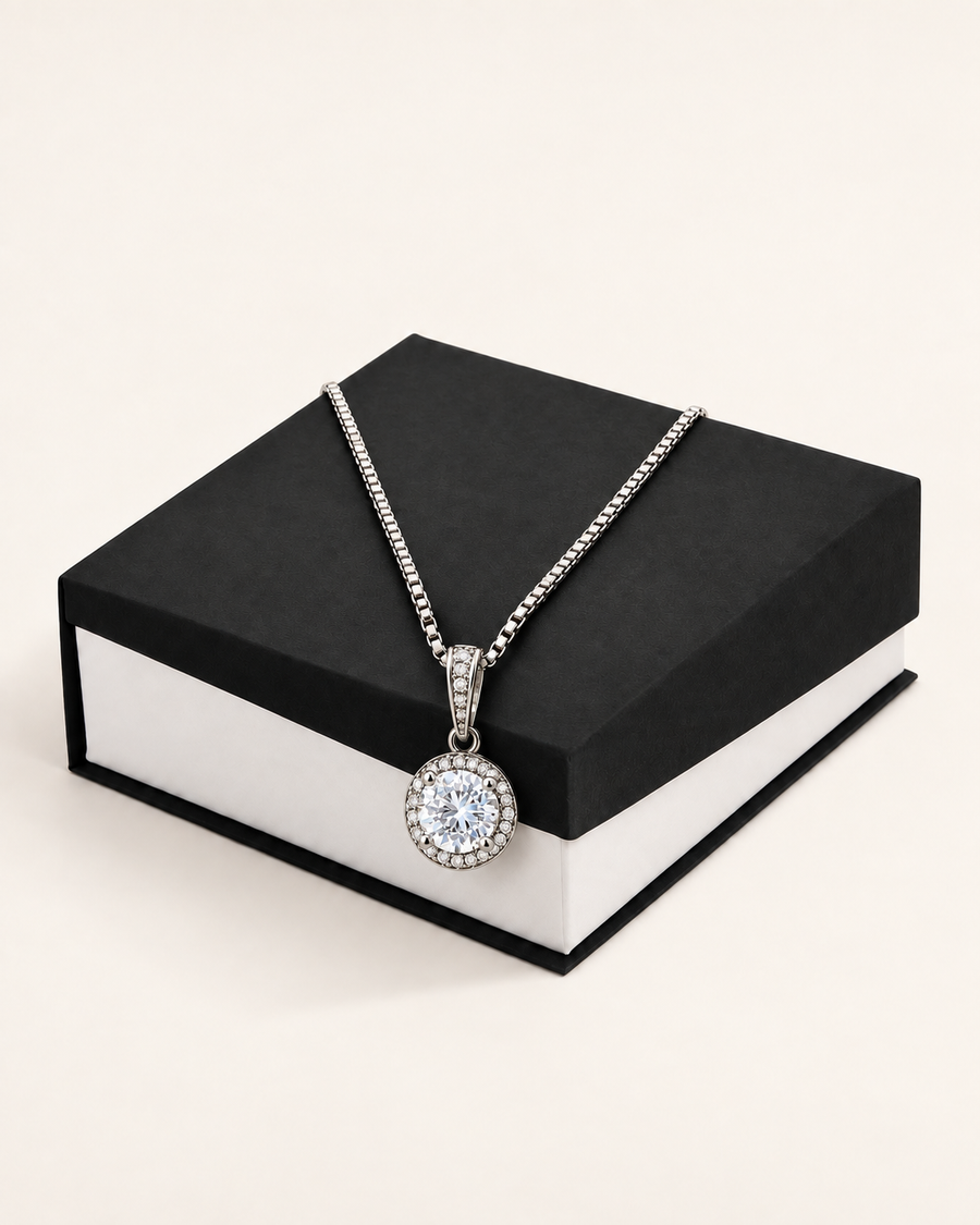 Silver-tone crystal halo pendant necklace displayed on a black gift box.