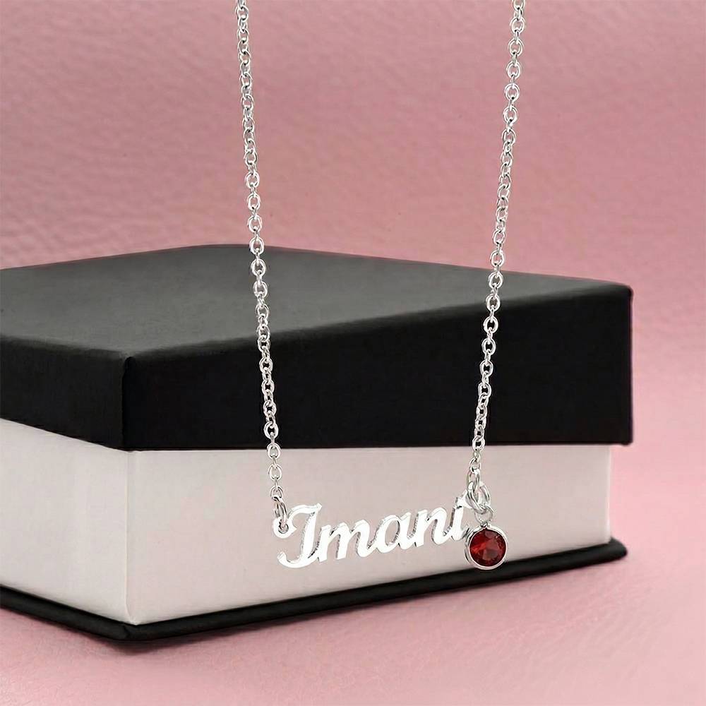 Silver-tone Emma name and red birthstone necklace displayed against a black gift box.