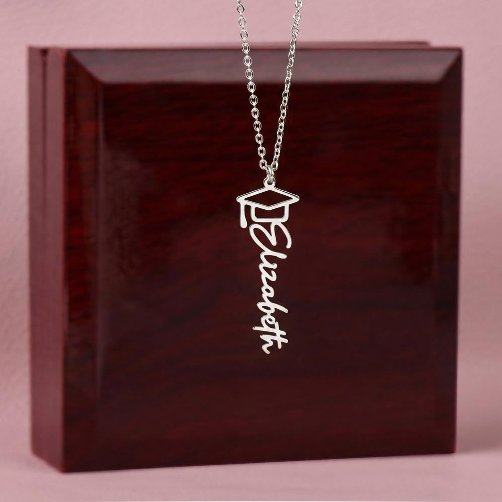 Silver-tone graduation name necklace displayed on a wooden gift box.