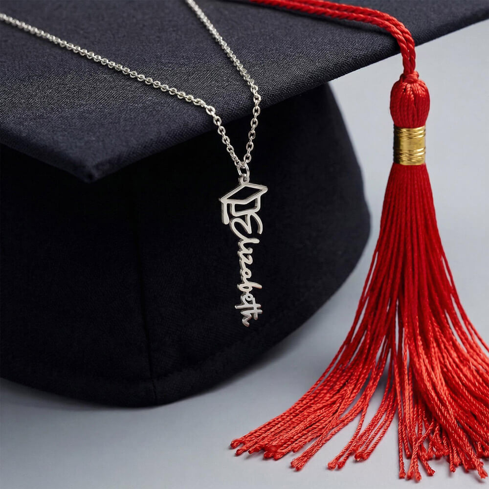 Silver-tone graduation name necklace draped on a black mortarboard with a red tassel.