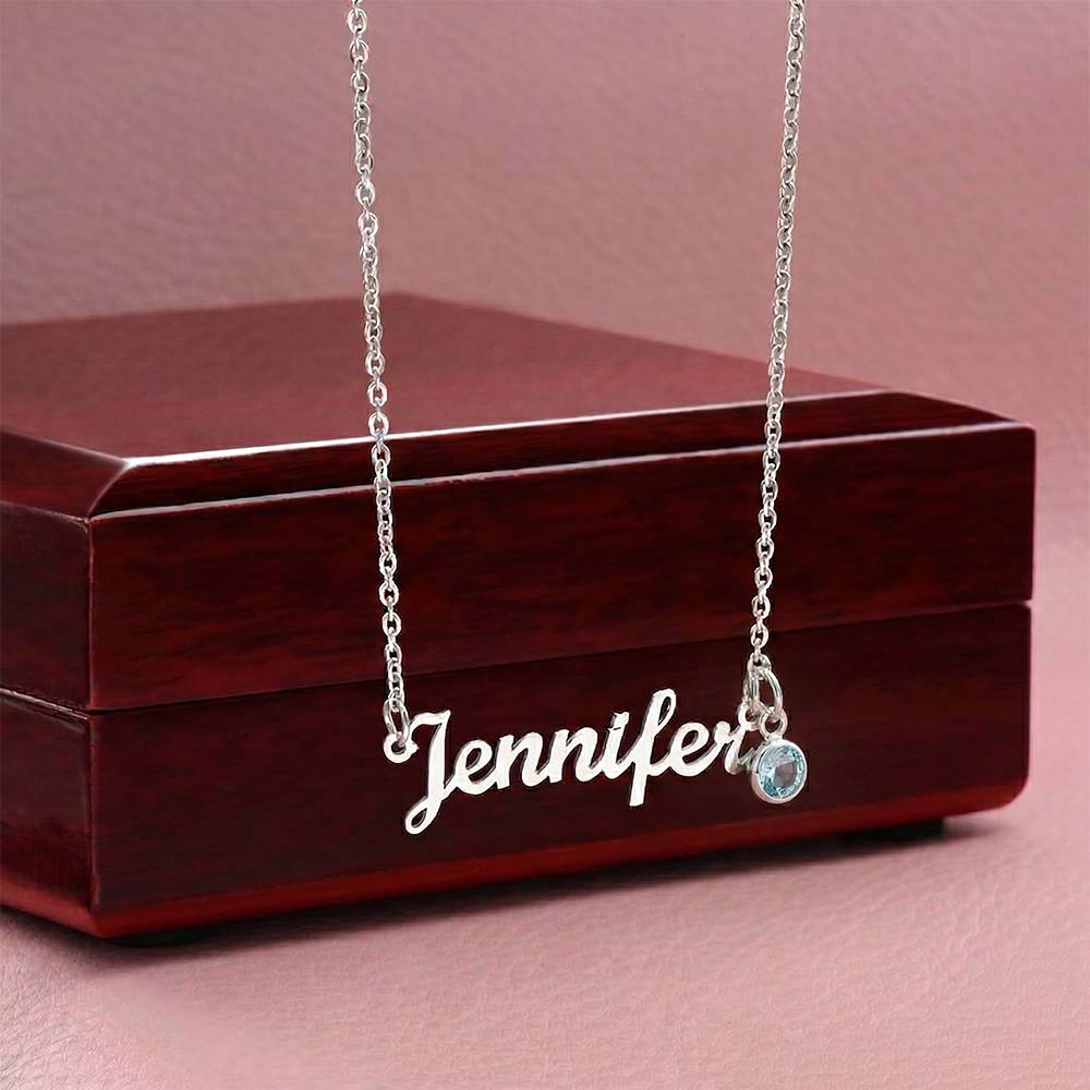 Silver-tone Jennifer name necklace with a pale blue birthstone displayed against a wooden gift box.