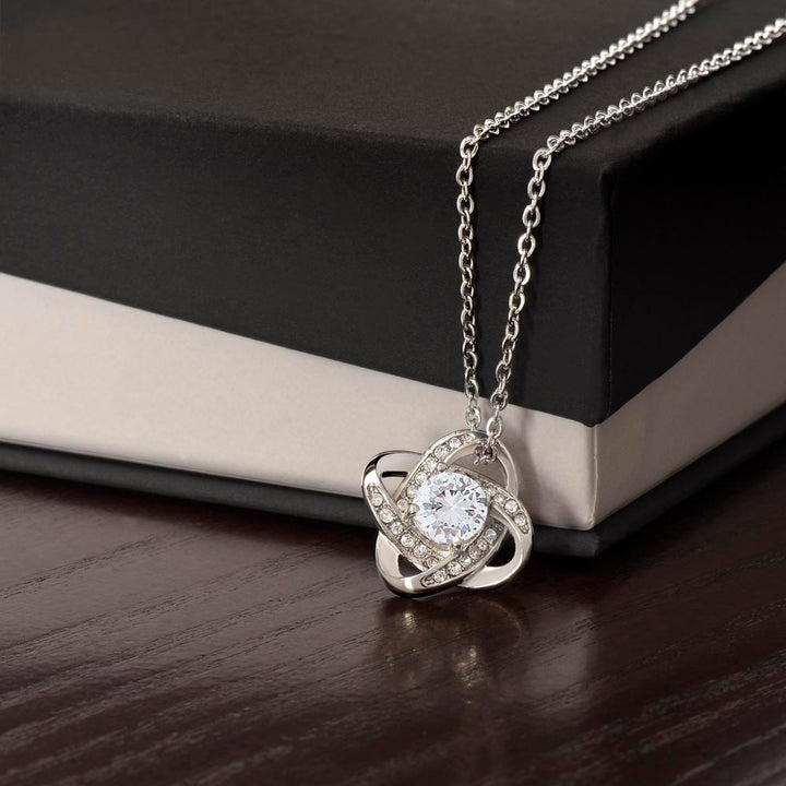 Silver-tone Love Knot CZ necklace displayed against a black gift box.