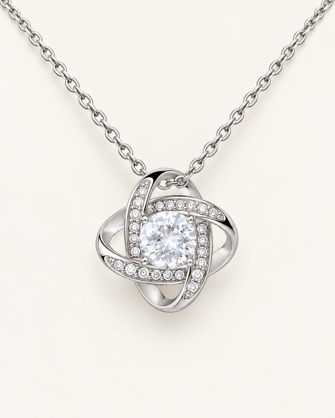 Close-up of a silver-tone Love Knot pendant with a round CZ center stone.